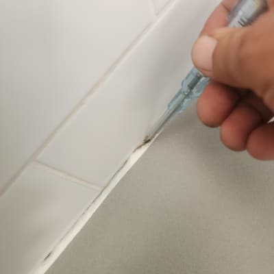 יד מחזיקה כלי בודק דליפות בין אריחים