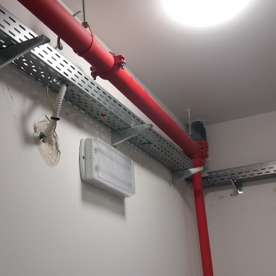 תעלות כבלים מתכתיות על קיר עם צינור אדום