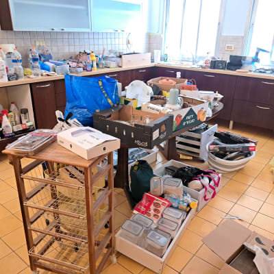 מטבח מבולגן עם מוצרי ניקוי וארגון על הרצפה והשיש