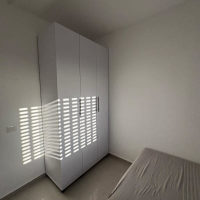 ארון בגדים לבן בחדר ריק עם מיטה