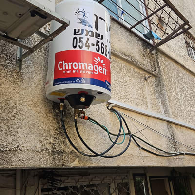 דוד שמש מותקן על קיר בניין עם צינורות מחוברים