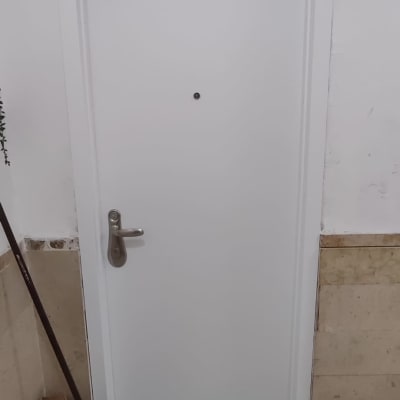 דלת לבנה עם ידית מתכת על רקע קיר לבן