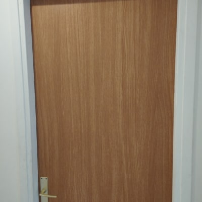 דלת עץ עם ידית מתכת במסגרת לבנה