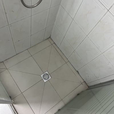 מקלחון עם אריחים לבנים וניקוז ברצפה