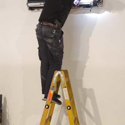 טכנאי מזגנים עובד על מזגן על סולם