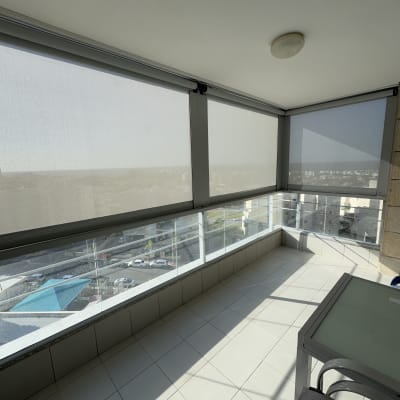 מרפסת עם סוככים נגללים על חלונות זכוכית