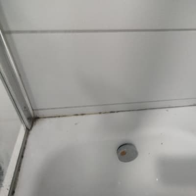 פינה של מקלחון עם דלת זכוכית ורצפת אמבטיה לבנה