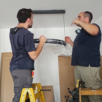 שני חשמלאים מתקינים גוף תאורה בתקרה