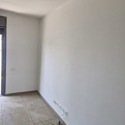 קירות ותקרה צבועים בלבן בחדר ריק לאחר עבודת צביעה