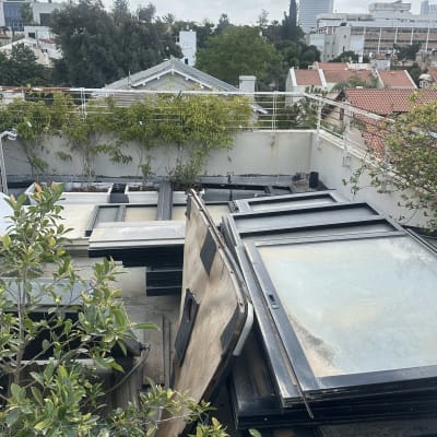 ערימות של חלונות ישנים על גג עם נוף עירוני ברקע