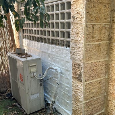 קיר אטום בחומר לבן ליד מזגן חיצוני