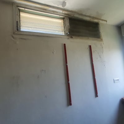 קיר עם סימני רטיבות ושני פרופילים אדומים