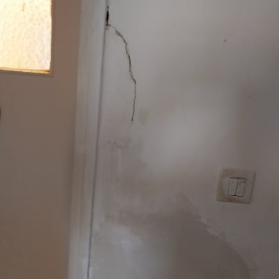 קיר עם סדק ותיקוני צבע ליד מתג חשמל