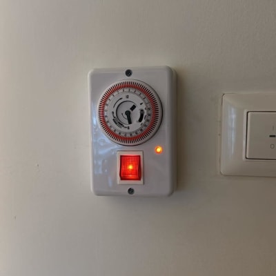 טיימר חשמלי עם מתג מואר על קיר