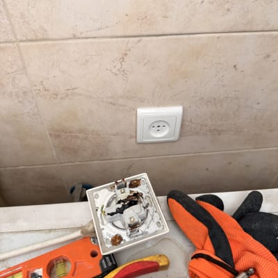 כלי עבודה ותשתית חשמל על רקע קיר אריחים