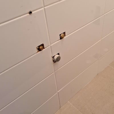 חיבורים וצינורות בקיר אריחים לבן