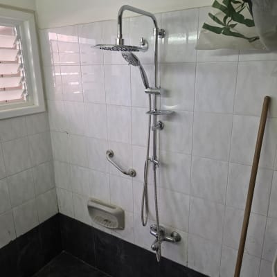 מקלחת עם אריחים לבנים וברזים כסופים