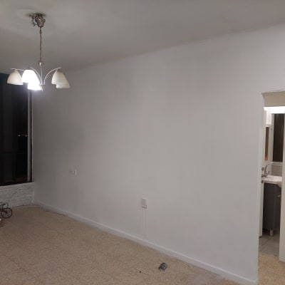 קיר צבוע בלבן עם שקי צבע על הרצפה