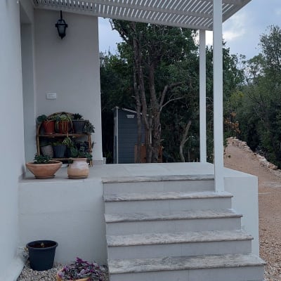 פרגולה מאלומיניום מעל מדרגות חיצוניות עם עציצים