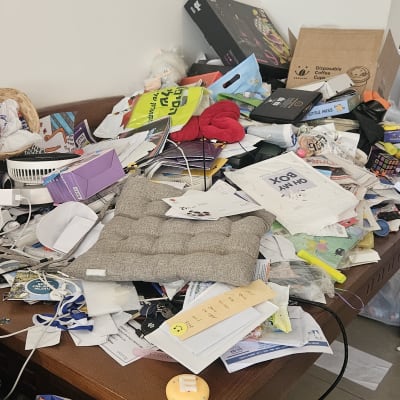 שולחן עמוס בניירות, קופסאות ופריטים שונים לא מאורגנים.