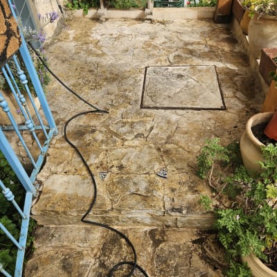 צינור מים שחור על רצפת אבן בחצר