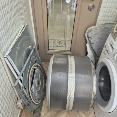 תוף מכונת כביסה מפורק ליד מכונה