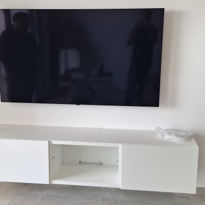 טלוויזיה מותקנת על קיר עם ארון לבן מתחת