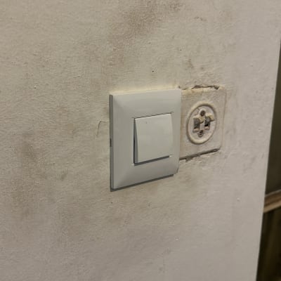 מתג חשמל על קיר לבן עם לכלוך קל