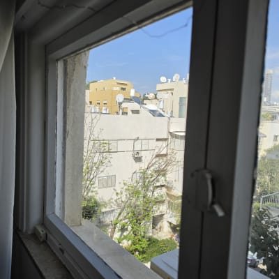 חלון זכוכית עם נוף לבניינים ועצים בחוץ