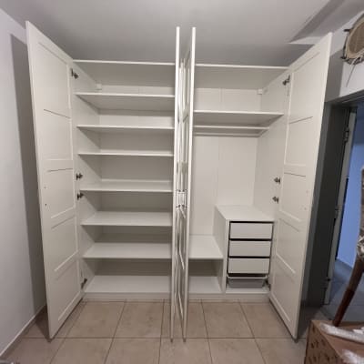 ארון לבן עם מדפים ודלתות פתוחות בחדר