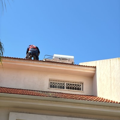 אדם עובד על דוד שמש על גג בית