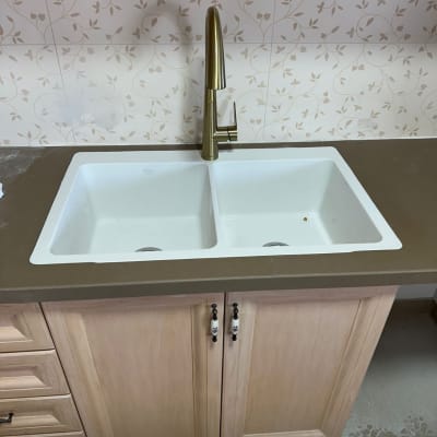 כיור כפול עם ברז זהב על משטח שיש במטבח