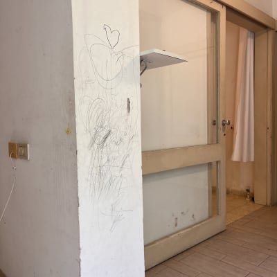 קיר עם כתמי צבע ושריטות ליד דלת זכוכית