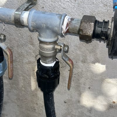 ברז מים עם צינור וחיבורים על קיר בטון