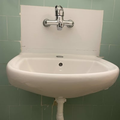 כיור לבן עם ברז כרום וצינור ניקוז