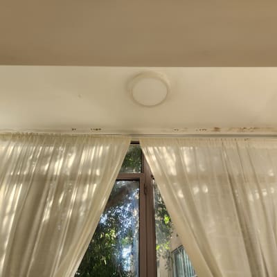 תקרה עם כתמי רטיבות ועובש ליד וילון לבן