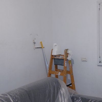 סולם עם כלי צבע ליד קיר לבן