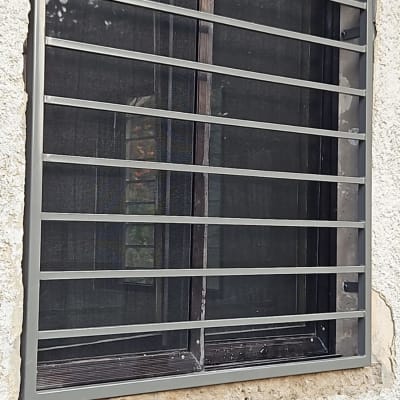 סורגי מתכת על חלון עם רשת כהה