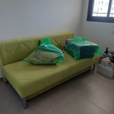 ספה ירוקה עם חפצים מכוסים בשקיות ירוקות