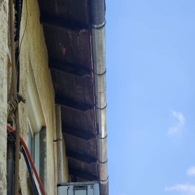 מרזב מתכת מחובר לגג עץ עם קורות חשופות