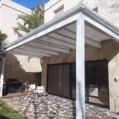 פרגולה לבנה מעץ בגינה עם ריצוף אבן