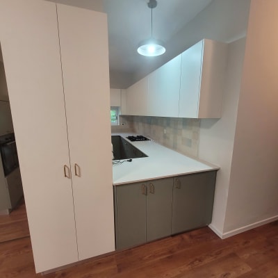 מטבח מודרני עם ארונות לבנים ומשטח עבודה בהיר