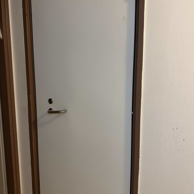 דלת לבנה עם ידית כסופה במסגרת חומה