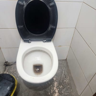 אסלה עם מושב שחור ומגבת על הרצפה