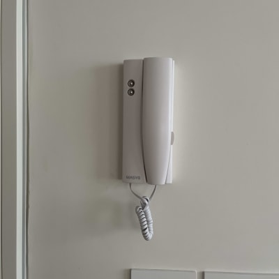 אינטרקום לבן עם שפופרת תלויה על קיר