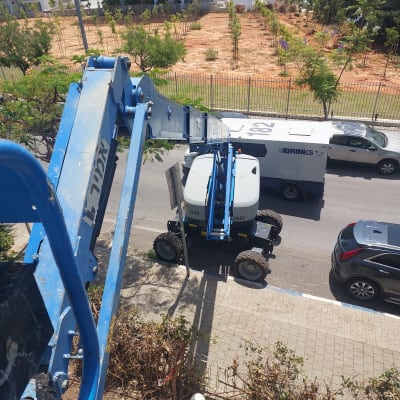 מנוף כחול ליד עצים לגיזום