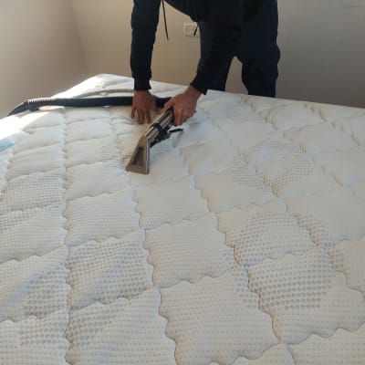 אדם מנקה מזרן עם שואב אבק