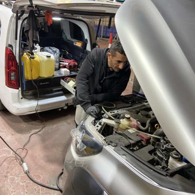 אדם מתקן רכב עם כלים ברכב שירות פתוח