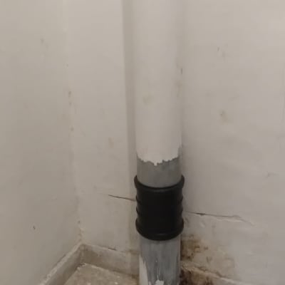 צינור ביוב עם חיבור בקיר על רצפת אריחים