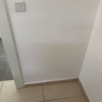 קיר פנימי צבוע בלבן ליד משקוף דלת ומתג תאורה